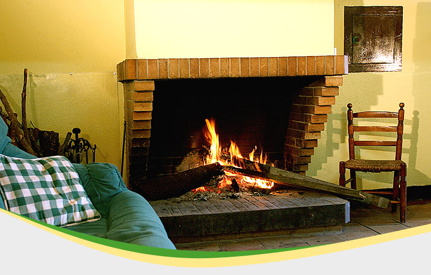 Chimenea con el fuego encendido. Al lado hay un sofá.